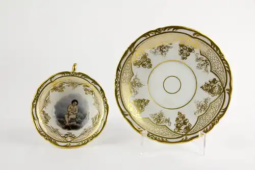 Tasse und Untertasse, Schlesien, Mitte 19. Jh., Gold- und Blumenmalerei, auf Tassengrund Darstellung eines pfeiferauchenden Puttos auf Wolke. H: 6 cm.