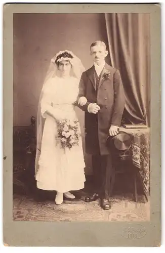 Fotografie G. Koczyk, Ort unbekannt, Portrait junges Paar in Hochzeitskleidung mit Schleier und Blumenstrauss