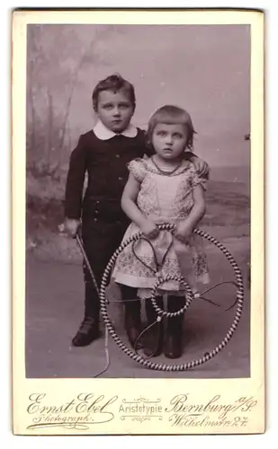 Fotografie Ernst Ebel, Bernburg a /S., Wilhelmstrasse 27, Portrait Kinderpaar in hübscher Kleidung mit Reifen