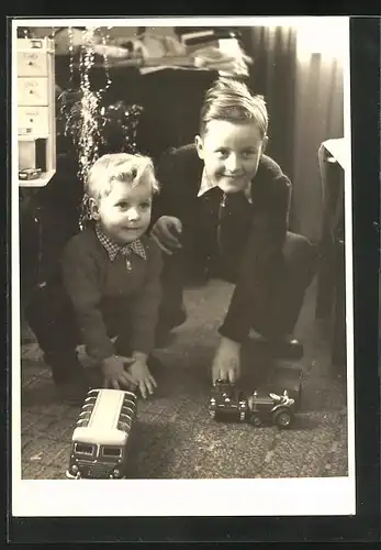 Foto-AK Brüder am Weihnachtsbaum mit ihrem Spielzeug, Panzer, Bus und Traktor mit Anhänger