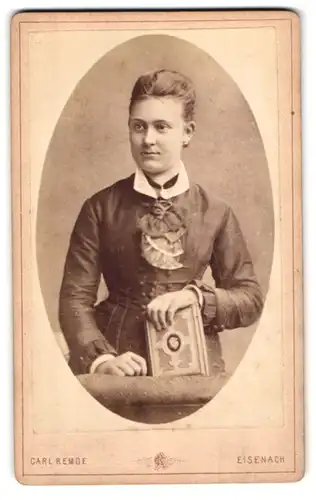 Fotografie Carl Remde, Eisenach, Portrait attraktive junge Frau im Biedermeierkleid mit Fotoalbum in der Hand