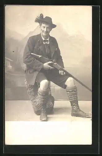 Foto-AK Jäger in Tracht hält sein Gewehr in der Hand, Studiokulisse