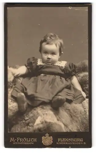 Fotografie M. Fröhlich, Flensburg, Norderhofenden 9, Süsses Kleinkind im Kleid sitzt auf Fell