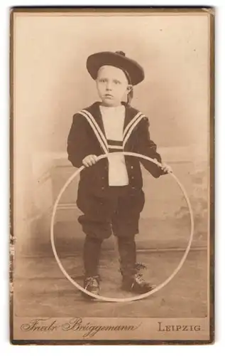 Fotografie Friedr. Brüggemann, Leipzig, Eisenbahnstr. 1, Portrait frecher Bube im Matrosenanzug mit Reifen in der Hand