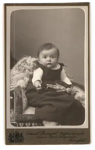 Fotografie Ernst Bingel, Bad Hersfeld a. d. F., Baby mit kleinem Püppchen auf einem Sessel