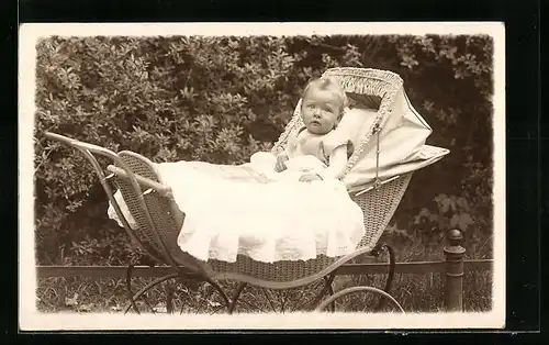 AK Baby sitzt in seinem Kinderwagen und schaut in die Kamera