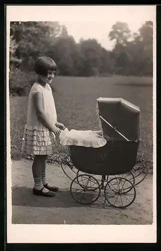 Foto-AK Mädchen mit Prinz Eisenherz-Frisur und Kinderwagen in einem Park