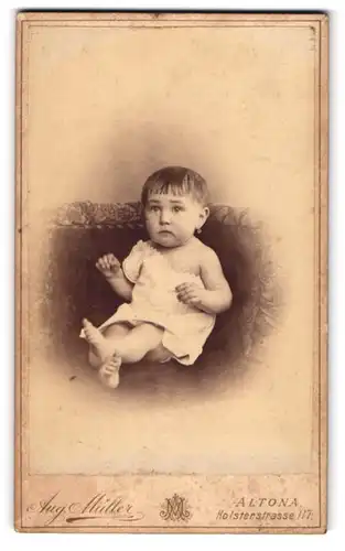 Fotografie Aug. Müller, Altona, Holstenstr.117, überrascht blickendes Kleinkind im schulterfreien Hemdchen