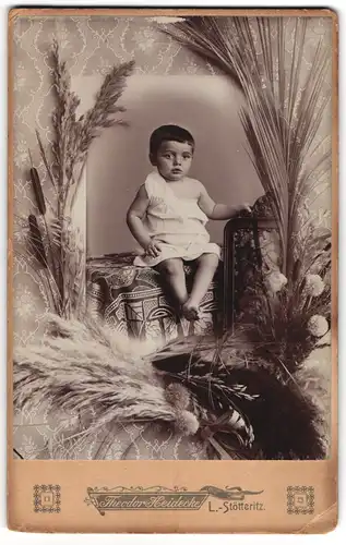 Fotografie Theodor Heidecke, Leipzig-Stötteritz, junger Knabe im Leibchen auf Tisch sitzend, Passepartout