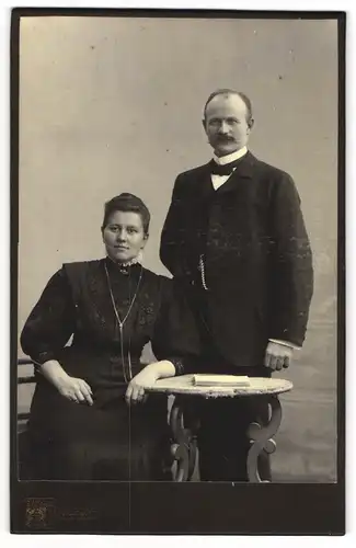 Fotografie L. Hüwel, Düsseldorf, Benratherstrasse, Elegant gekleidetes Paar am Tisch