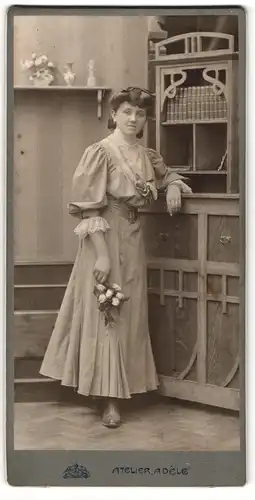 Fotografie Atelier Adele, Karlsbad, junge Dame im Kleid posiert in einer Studiokulisse, Jugenstil Schrank