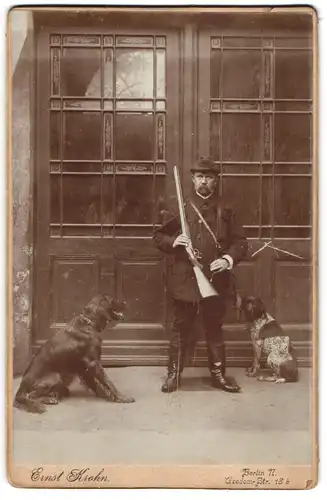 Fotografie Ernst Krahn, Berlin, Jäger mit Flinte und seinen beiden Jagdhunden