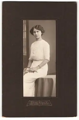 Fotografie Ernst Stautz, Eschwege, Portrait weiss gekleidete Dame mit Blumen auf Tisch sitzend