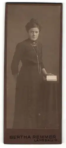 Fotografie Bertha Remmer, Langballig, Junge Frau in Tracht mit hochgesteckter Frisur, Halsschmuck und Buch in der Hand