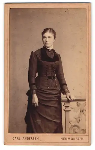 Fotografie Carl Andersen, Neumünster, Junge Dame in tailliertem Kleid mit leichtem Lächeln und Hochsteckfrisur