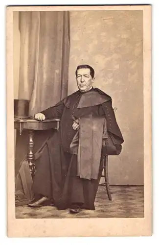 Fotografie A. Pech & H. Fiedler, Ort unbekannt, höherer Geistlicher im Gewand nebst Zylinder auf dem Tisch