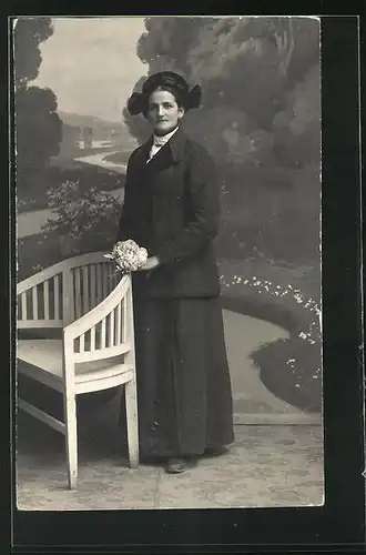 Foto-AK Elegante Dame mit Blumen an Bank gelehnt vor einer Studiokulisse