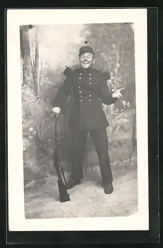 Foto-AK Fröhlicher Soldat in Uniform vor Studiokulisse