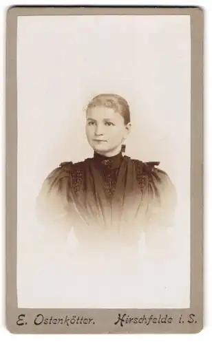 Fotografie E. Ostenkötter, Hirschfelde i. S., Junge Dame trägt ein dunkles Kleid mit Puffärmeln