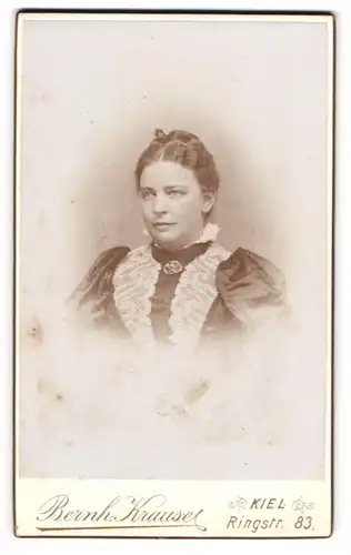 Fotografie Bernh. Krause, Kiel, Portrait junge Dame im eleganten Kleid mit Kragenbrosche