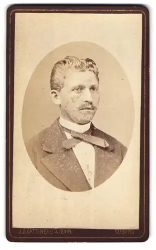 Fotografie J. G. Gattineau & Sohn, Coburg, Portrait stattlicher blonder Mann mit Schnäuzer und Fliege im Jackett