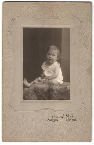 Fotografie Franz J. Mock, Saulgau, Kleinkind im Kleid auf Fell sitzend