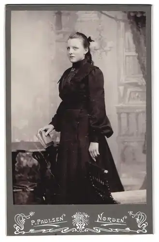 Fotografie P. Paulsen, Norden, Junge Frau im Trachenkleid und zurückgebundener Frisur mit Buch in der Hand