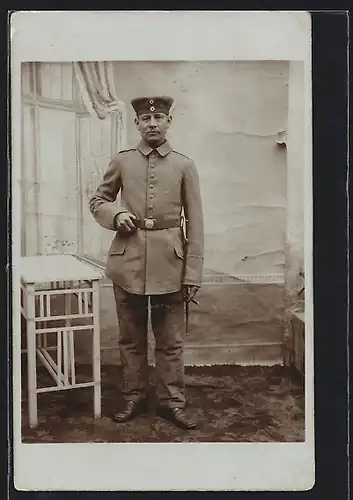 Foto-AK Soldat in Feldgrau Uniform mit Bajonett und Krätzchen