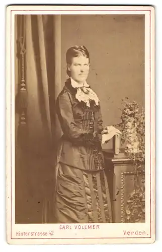 Fotografie Carl Vollmer, Verden, Hinterstr. 42, Elegante Dame mit Flechtfrisur stehend in festlichem Kleid