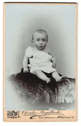 Fotografie Charles Angelbeck, Cuxhaven, Mittelstrasse 2, Baby sitzt auf einem Fell