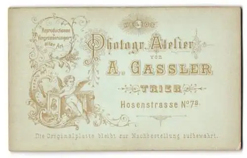 Fotografie A. Gassler, Trier, kleiner Engel sitzt vor einer Plattenkamera und hält Fotografie in der Hand