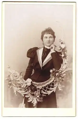 Fotografie unbekannter Fotograf und Ort, junge Frau im Kleid lehnt an einer Jugendstil Ornamentik, Studiokulisse