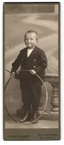 Fotografie Herm. Zieger, Aschersleben, Breitestr. 27, Der junge Werner Blumgarten im Anzug mit einem Reifen