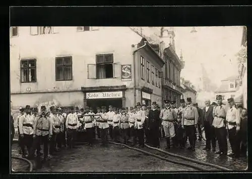 Foto-AK Feuerwehrmänner mit Löschschläuchen vor einem Foto-Atelier