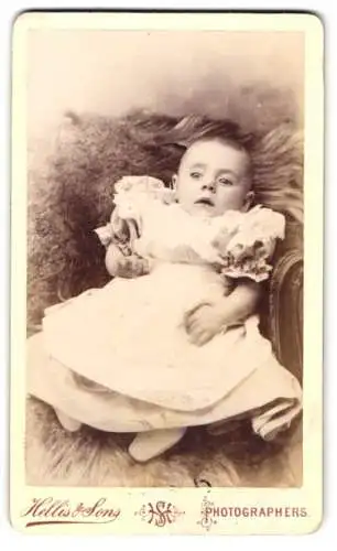 Fotografie Hellis & Sons, London, 160 High Street, Niedliches Baby im weissen Kleid mit seichtem Haar und fragendem Blick