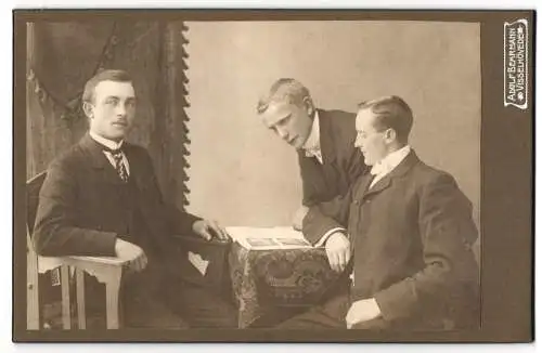 Fotografie Adolf Behrmann, Visselhövede, Drei junge Männer im Anzug an einem Tisch