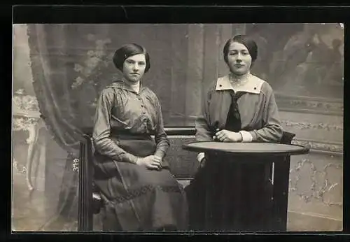 Foto-AK Junge Frau und Mädchen am Tisch in einer Studiokulisse