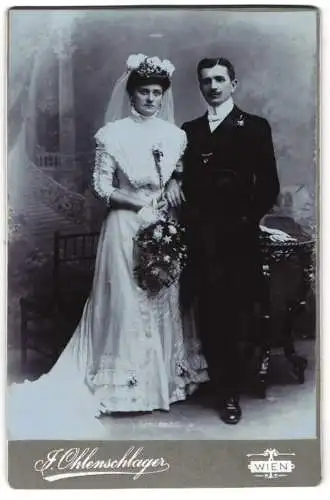 Fotografie J. Ohlenschlager, Wien, Brautpaar Zafauk im Hochzeitskleid und Anzug mit Brautstrauss