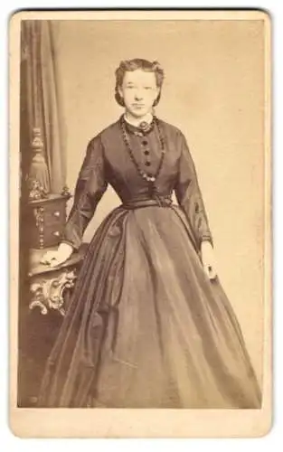 Fotografie A. Fröhlich, Nördlingen, junge Frau im taillierte dunklen Kleid mit Halskette