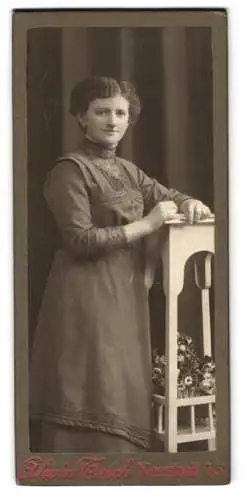 Fotografie Alwin Teich, Neustadt i. S., Junge Frau im Kleid an einem weissen Regal mit Blumen