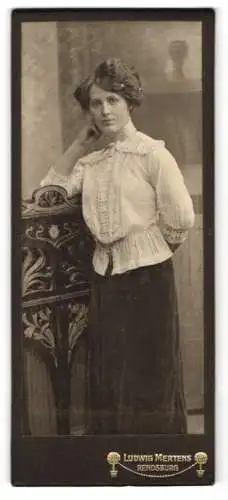 Fotografie Ludwig Mertens, Rendsburg, Bürgerliche Dame in verzierter Bluse an einer Kommode