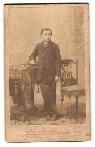 Fotografie Atelier C. Schmitz, Reichenbach i. V., Bahnhofstrasse, Junge im Anzug mit der Hand auf einem Buch