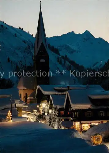 AK / Ansichtskarte Mittelberg_Kleinwalsertal Ortsmotiv mit Kirche zur Weihnachtszeit Winterlandschaft im Abendlicht  Mittelberg_Kleinwalsertal Kat. Oesterreich