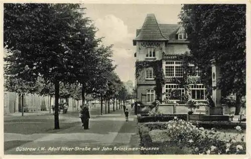 AK / Ansichtskarte 73974299 Guestrow_Mecklenburg_Vorpommern Strassenpartie mit John Brinckman-Brunnen